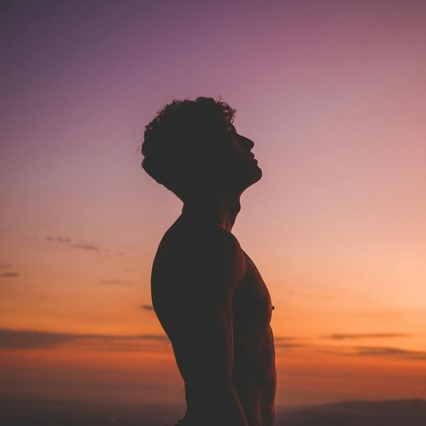 Silhouette of a person in a meditative pose against a warm sunset.